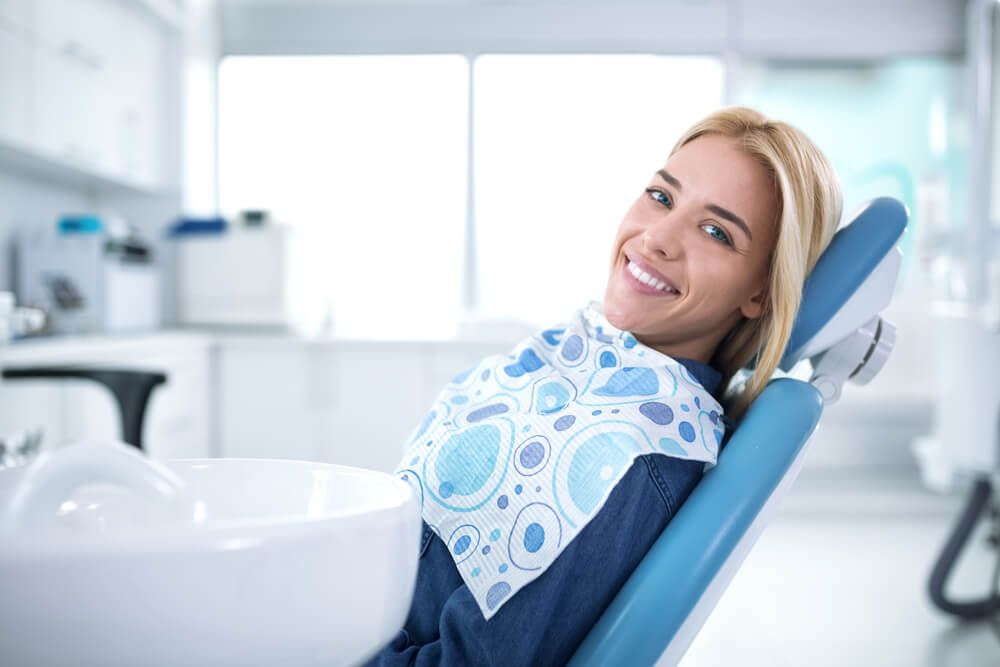 Smiling patient seated in a bright dental office