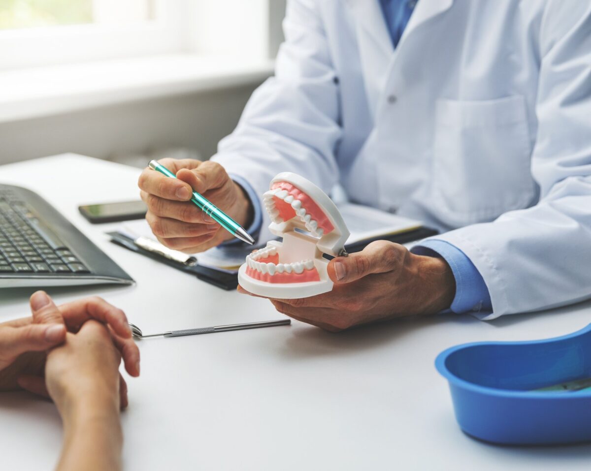 Dentist showing a patient a tooth model while discussing a planned cosmetic dentistry treatment