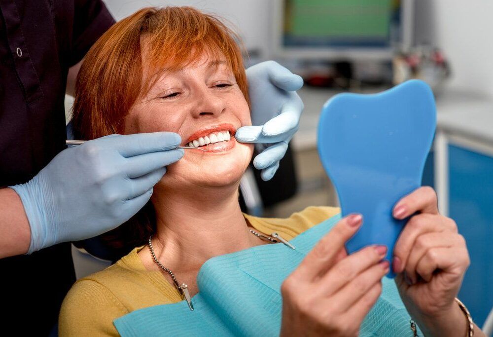 Patient holding a hand mirror during a dental visit