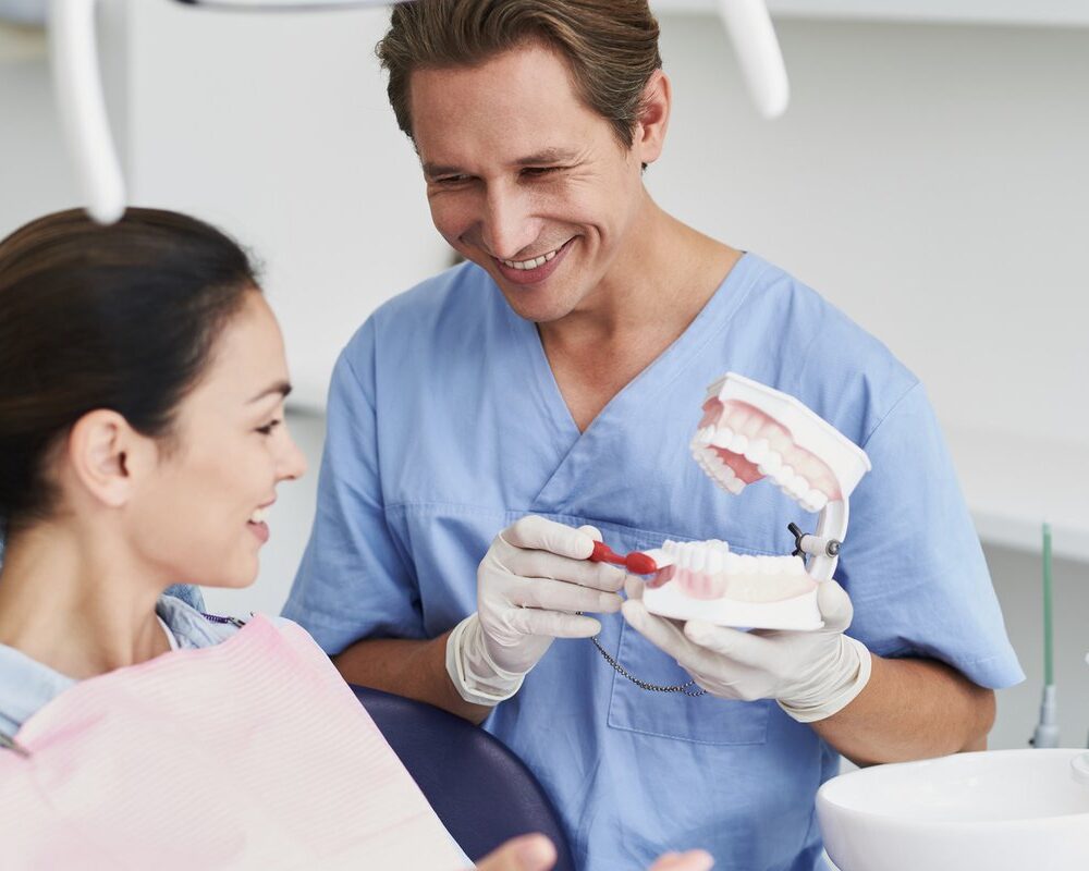 Dentist showing a tooth model to a smiling patient