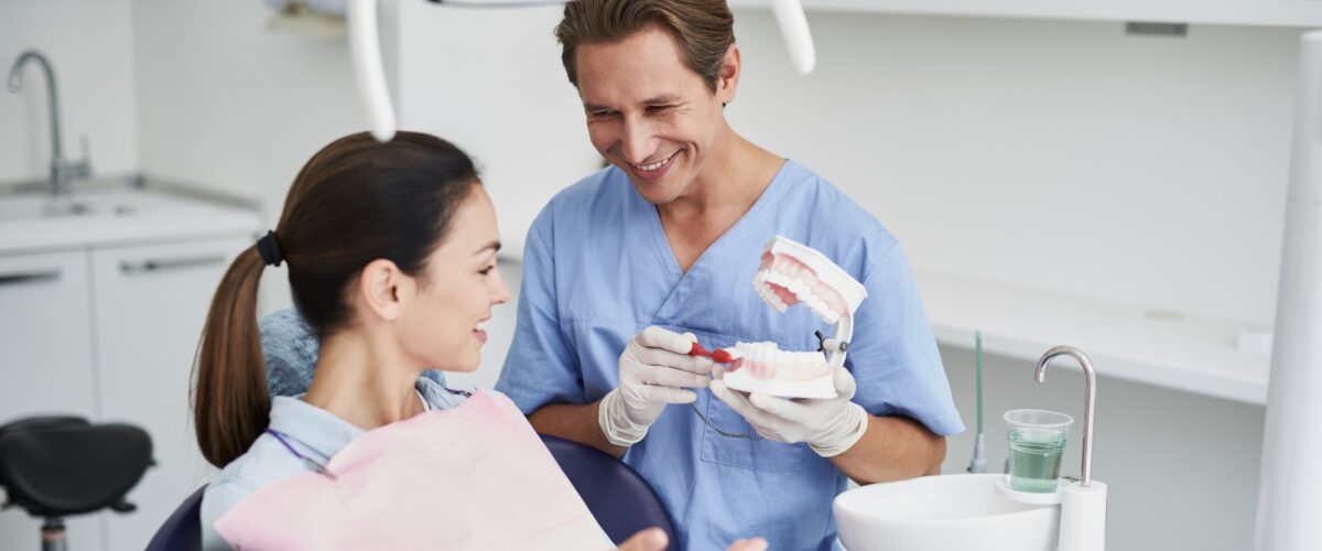 Dentist showing a tooth model to a patient